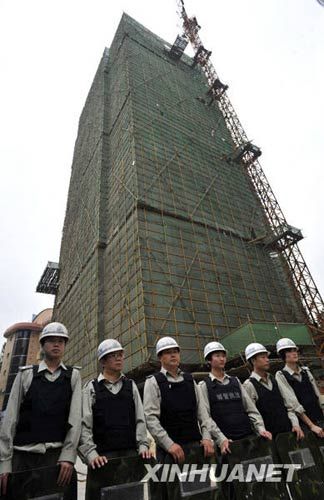 10月27日,城管队员在违建楼下维持秩序。新华社发